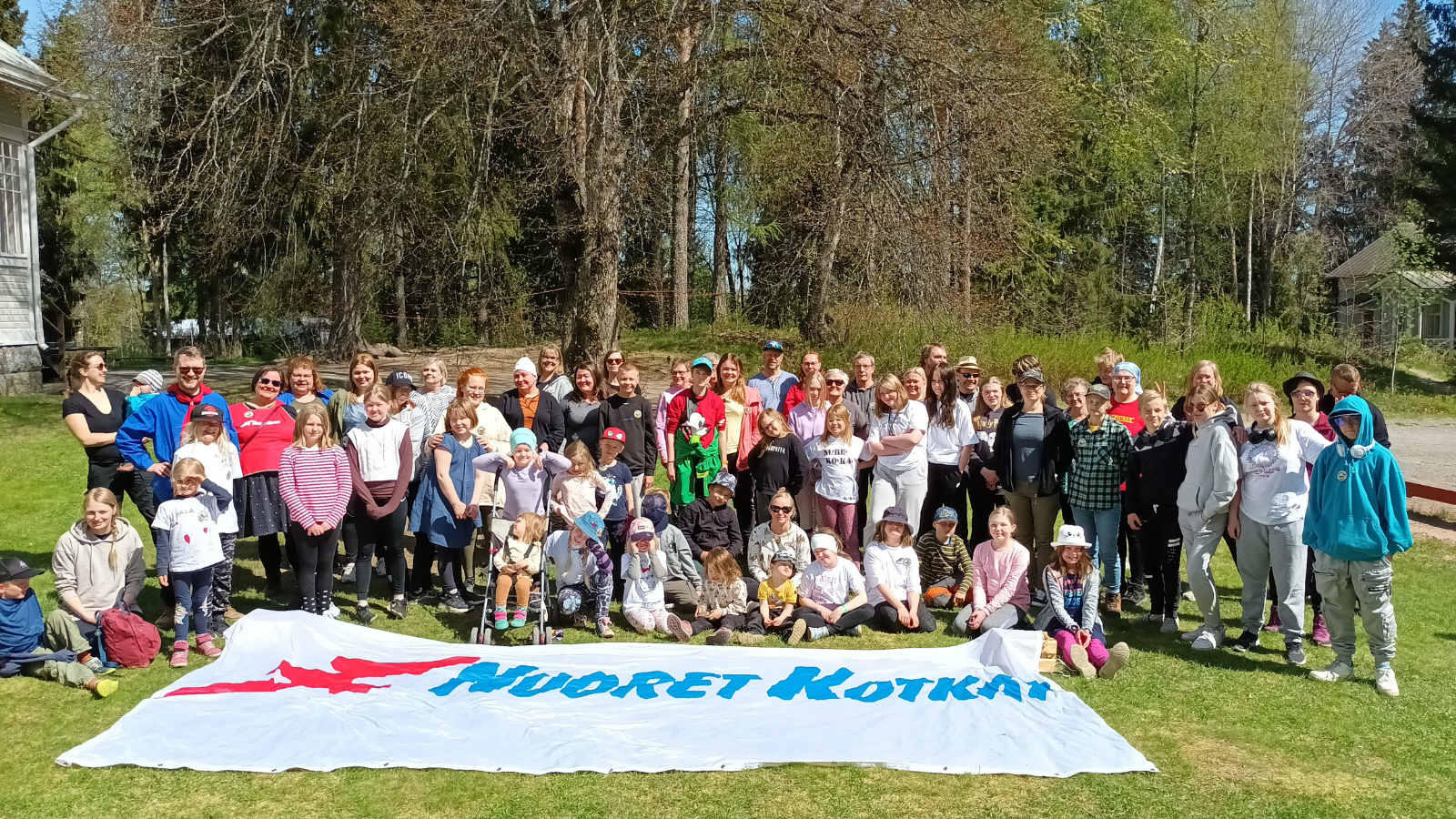 Osallistujat Nuorten Kotkien lipun takana Sorjan kesäsiirtolan pihassa.